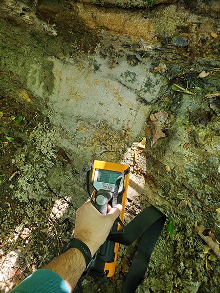 Geologist field screening an outcrop for naturally occurring radioactivity using a portable gamma spectrometer